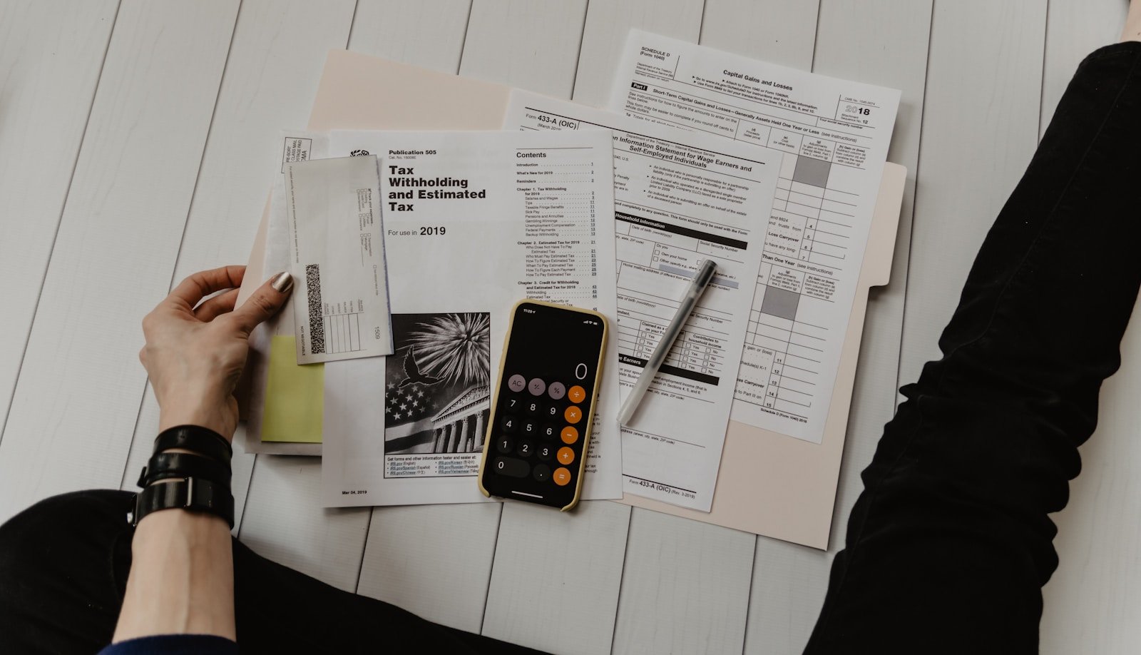 Best 5 Apps to Manage Personal Finances For You 1 person holding paper near pen and calculator