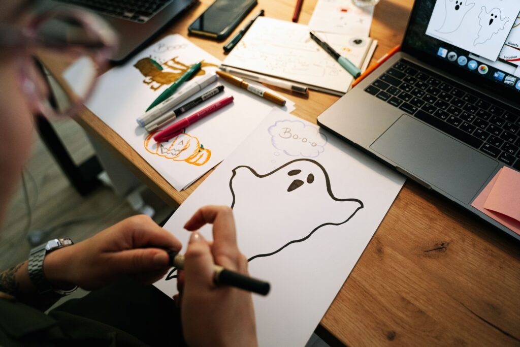 Person drawing Halloween ghosts and pumpkins