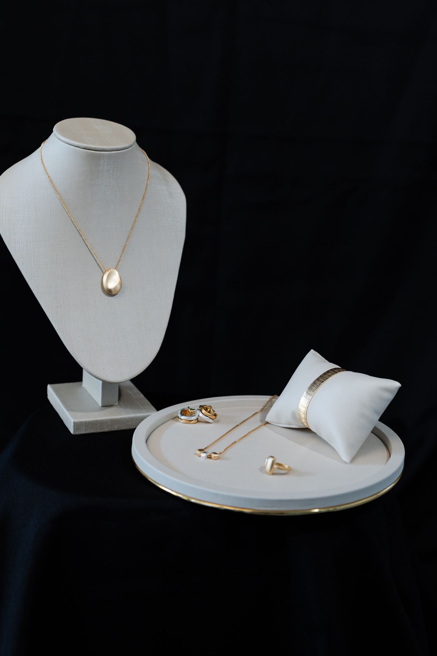 Illustrative gold necklace and earrings on a dark display